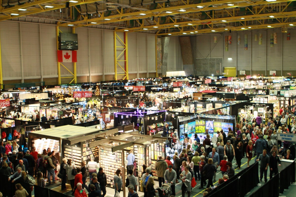 Large indoor convention center with numerous booths and people walking around.