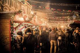 Crowd of people at a festive market with lights and decorations